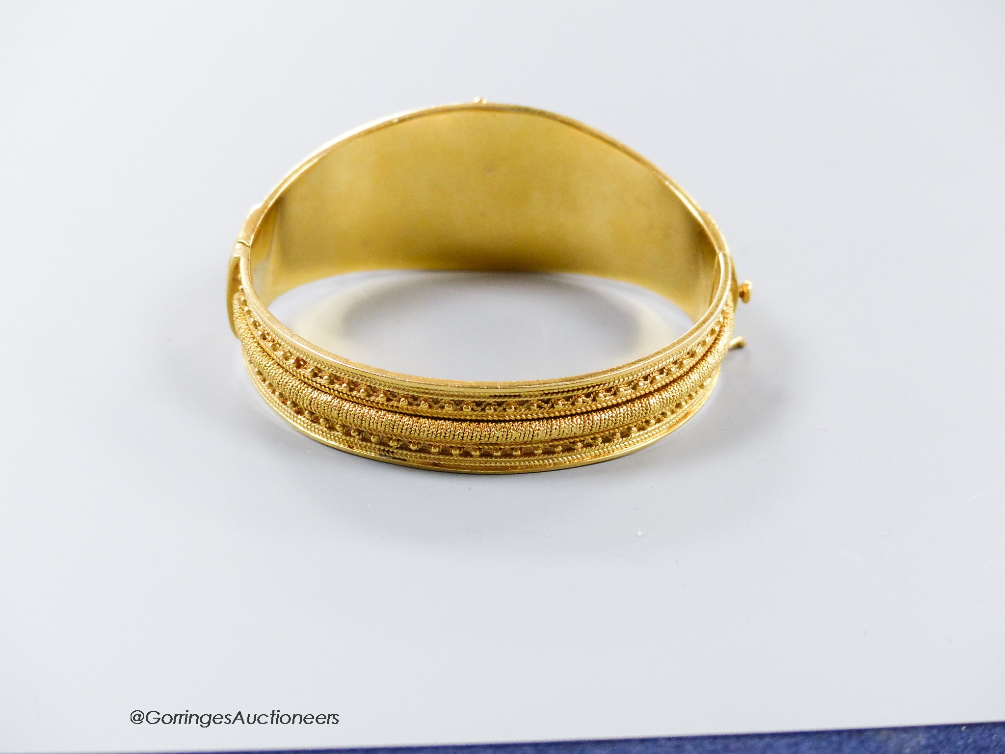 A 20th century Victorian style yellow metal (stamped 19k) cannetile work hinged bracelet, interior diameter 57mm, 60.1 grams.